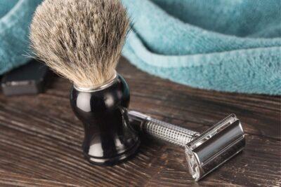 Photo of a safety razor lying next to a shaving brush