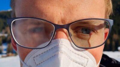 Close view of a man's face wearing glasses with a mask over his nose and mouth