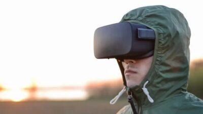 Man in military uniform with a green hoodie, and wearing VR goggles