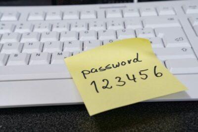 Image of a keyboard with a yellow sticky note on it, saying password123456