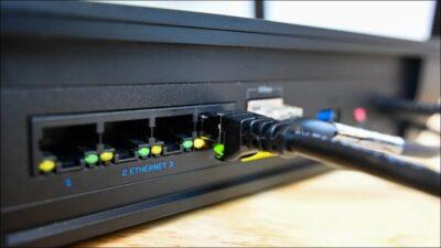 Rear of a router showing it's Ethernet ports, with one Ethernet cable plugged into one of the ports