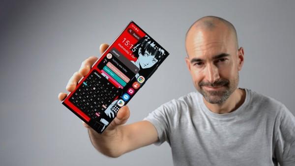 Man holding a phone facing us, and phone screen shows some widgets including large calculator widget, with icons running down the right hand edge