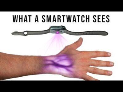 Image of smartwatch above a hand, with violet light shining down on the hand, which reveals the veins