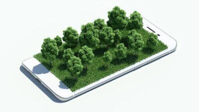 Phone with the screen that has grass and small trees growing off its surface.