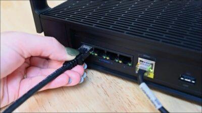 Hand plugging an Ethernet cable into the port of a router