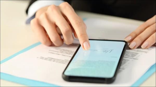 Two hands holding smartphone, which is resting on a printed paper form