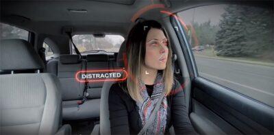 Front view of a femal driver in a car, with her eyes being scanned by red light