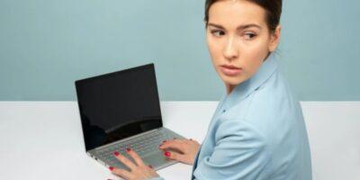 Woman typing ona laptop with blank screen, and looking back over her shoulder