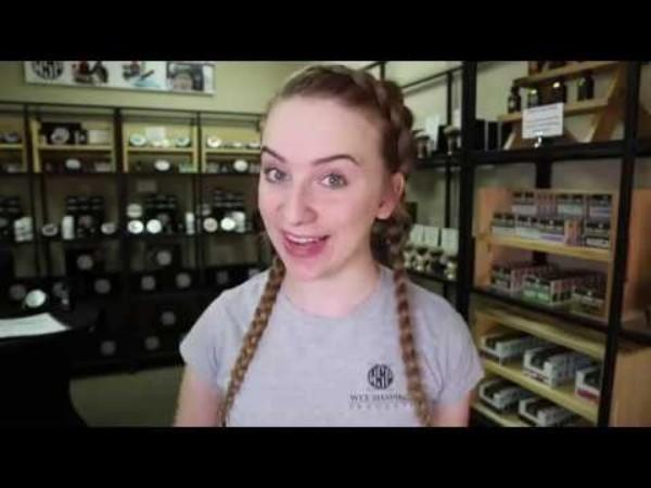 Woman with long pigtails in her hair, and background has various shaving supplies on many shelves