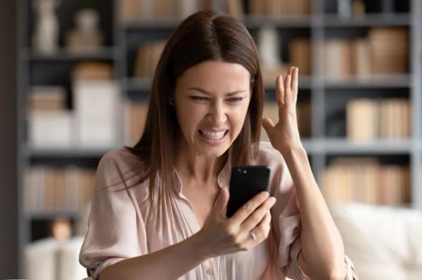 Woman holding phone and looking very frustrated