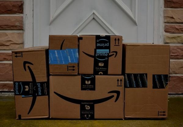 Five Amazon shipping cardboard boxes standing in front of a white door