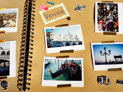 View of a photo album page, with yellow background, and the title "Venice" at the top left with a sticker of a plane next t o it. Four photos on the page depict scenes in Venice such as two moored gondoliers, the top of Basilica di San Marco, some street lights, and whole lot of typically Venetian masks.