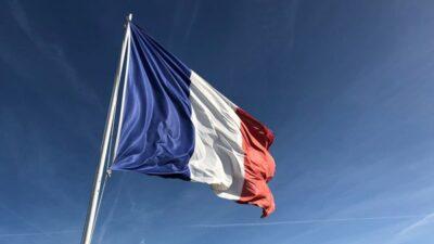 French flag flying on a flag pole with blue sky behind it