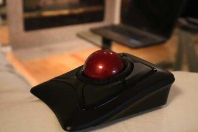 A black trackball mouse with a dark red ball on the top