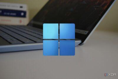An open laptop in the background, with a blue square shaped Windows logo in the foreground