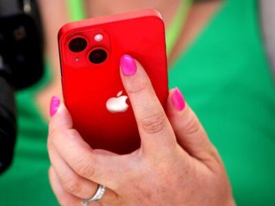 Rear view of a bright red iPhone, being held by a hand