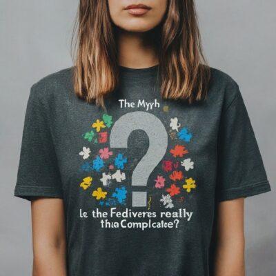 Woman wearing a grey T-shirt with a large question mark, and the words The Myth Is the Fediverse really that complicated". Only the bottom half of the women's face is visible, with brown shoulder length hair.