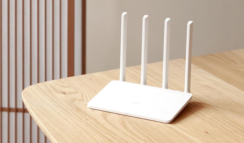 A white plastic covered WiFi router with 4 vertical antennas at the back of it