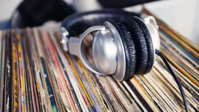 Stack of vinyl records with a pair of wired headphones resting on top