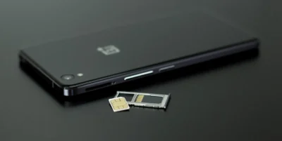 Smartphone lying face down, with SIM tray next to it, with a loose SIM card