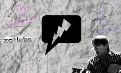 Piece of paper in background covered in pencilled notes and calculations. In the centre is a black rectangle with a white lightning bolt through it. Bottom right is the head and shoulders of a man wearing glasses and wearing a checked shirt. Top left is a symbol with the words ActivityPub Rocks. To the top right is a symbol with the words Hubzilla rules.