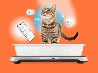 A flat white scale with a cat litter box on top. A cat is standing in the litter box. To the left is a smartphone superimposed on the picture, and superimposed over the cat is a weight graph line and the words "3 visits" with a weight shown of 7.6 lbs weight.