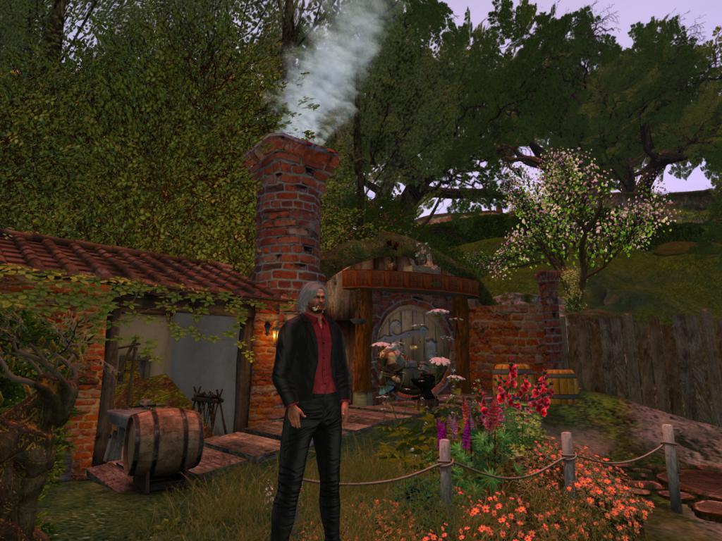 Avatar dressed in a black jacket and pants, with a dark red shirt. He has long grey hair and is smoking a pipe. Behind him is a hobbit like scene with lots of green trees and red brick home with white smoke emitted from the chimney. In front of the house a blacksmith is working at a fire. In the foreground are lots of colourful bushes and flowers.