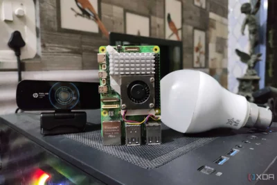 A Raspberry Pi computer standing on top of a computer case. On the left side is a webcam, and on the right side is a white LEB bulb.