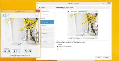 Two windows are shown open - one on the left is titled DroidCam Client and shows a preview of some flowers standing in a glass of water, with some icons at the bottom to increase/decrease zoom, brightness, autofocus, and switching perspective and rotating the image. The rightmost window is titled Skype Options and shows the video settings selected, with the source name as DroidCam Source 1, and the same preview image is shown of the flowers in a glass of water.