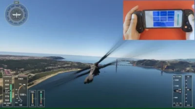 Microsoft Flight Simulator view from behind an aircraft, with it flying towards a bridge in the background and some land on either side covered with trees and greenery. Bottom left, and bottom right are shown some gauges such as airspeed, power, fuel level, altitude, etc. Top right is an insert showing two hands holding a smartphone in landscape position with 7 blue buttons on the screen. To each side of the phone are two game controller attachments fastened to the side of the phone.