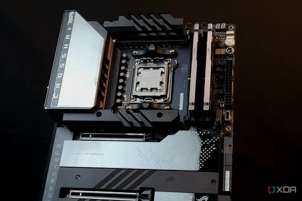 Part of a computer motherboard showing the square CPU socket with the lever that holds it tight, and to the right of it we can see two sticks of RAM standing vertically on the board.