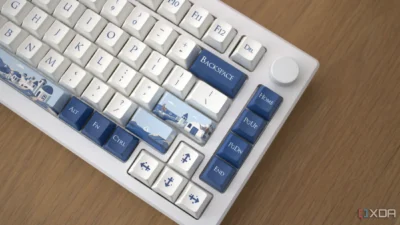 A white keyboard showing some buttons with a blue background colour such as the backspace, home, pgup, pgdn, end, alt, fn, and ctrl. The enter and space keys have images on them like cottages set against a sea view.