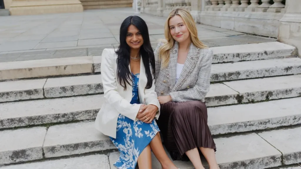 Two women sitting side by side on some white stone steps.