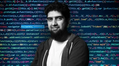 Man smiling at camera with dark hair and a beard. Behind him is a terminal screen covered in lots of different source code with many words highlighted in different colours. The words PASSWORD(