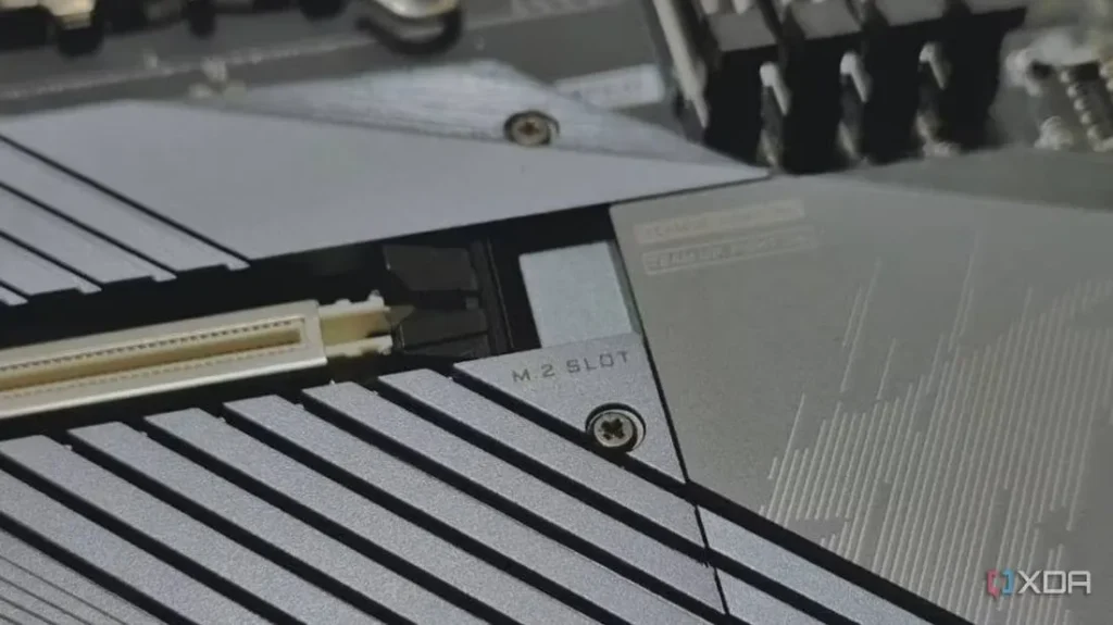 Close up view of part of a computer motherboard showing a M.2 slot made from white plastic with fine pin-hole size holes along its length on each side.