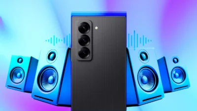 Rear side of a smartphone with three round camera lenses. On either side are seen two pairs of speakers, each with a large bass woofer and one small treble woofer above it.