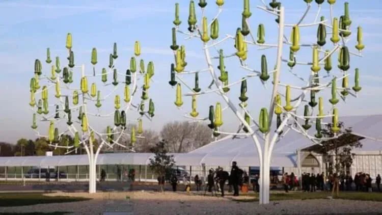 Two wind energy generation units designed to look like trees. The trunks and branches are a white material, and the "leaves" look like green vertical shaped cones.