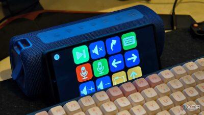 A blue Bluetooth speaker stands beside a touchscreen device displaying colorful control buttons and a vintage-style keyboard.