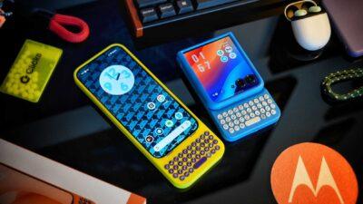 Two stylish Motorola phones on a dark surface: a yellow smartphone with a colorful display and a blue, keyboard-equipped model beside it. Both phones have Clicks hardware keyboards attached, and the keyboards form part of a case that wraps around the phone's own shapes.