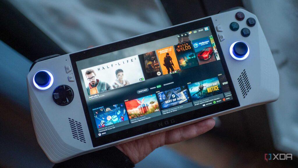 A person holding a handheld gaming device displaying a library of games, featuring titles like "Half-Life 2" and a vibrant interface.