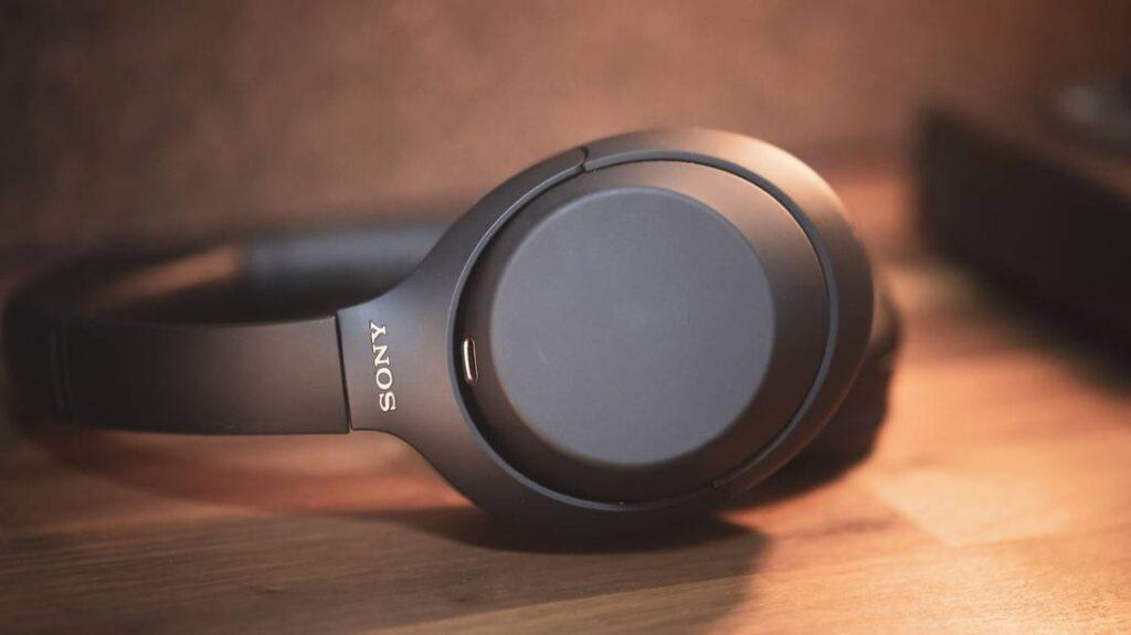 Close-up of black Sony headphones resting on a wooden surface, showcasing sleek design and glossy accents.