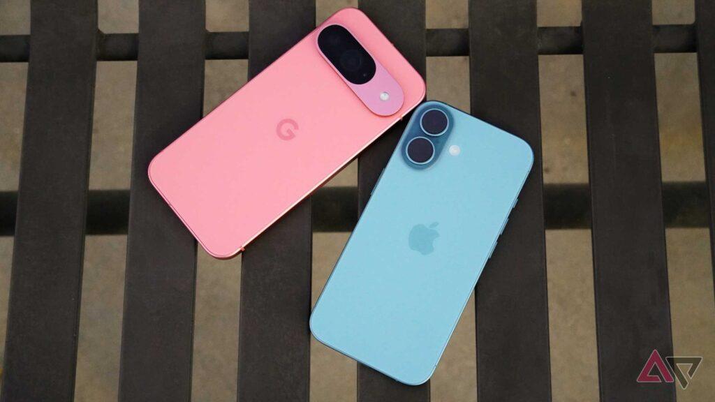 Two smartphones, a pink Google Pixel and a blue Apple iPhone, resting on a wooden table, showcasing their sleek designs.
