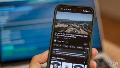 A hand holds a smartphone displaying a documentary titled "476 AD - A Tour Of Europe" with a scenic landscape background.