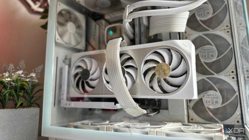 A close-up of a high-end graphics card with dual white fans inside a sleek computer case, surrounded by cooling fans and decorative plants.