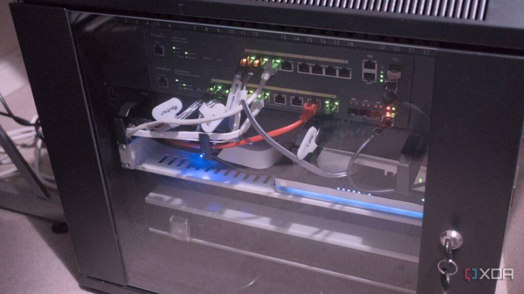 A network rack cabinet with multiple switches and cables, displaying active lights indicating power and connectivity.