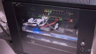 A network rack cabinet with multiple switches and cables, displaying active lights indicating power and connectivity.