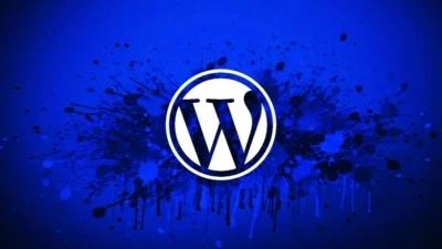 WordPress logo in white, centered on a vibrant blue background with splashes of darker blues and black paint for an artistic effect.