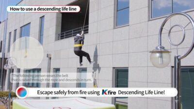 A person descends a building using a Kfire Descending Life Line, demonstrating safe escape techniques from a fire.