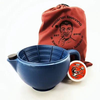 The Intergalactic Indestructible Shatterproof Travel Scuttle by Phoenix Shaving 6 A blue shaving bowl with a textured interior, a red drawstring bag with branding, and a circular shaving soap container.