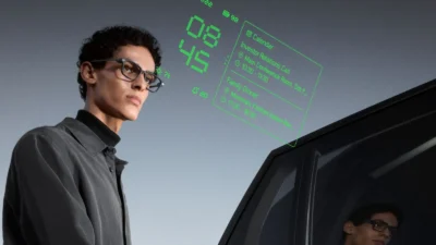 A person in a black shirt stands next to a futuristic car, with a digital interface displaying the time and calendar events.